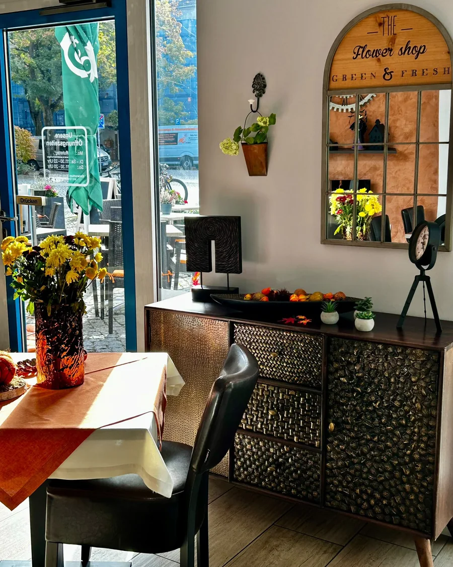 Gedeckter Tisch mit herbstlicher Dekoration und Sideboard im Gastraum